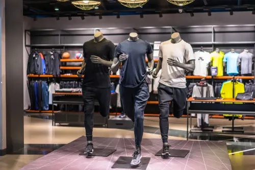 Three mannequins dressed in athletic wear are displayed in a sports apparel store, set in running poses.