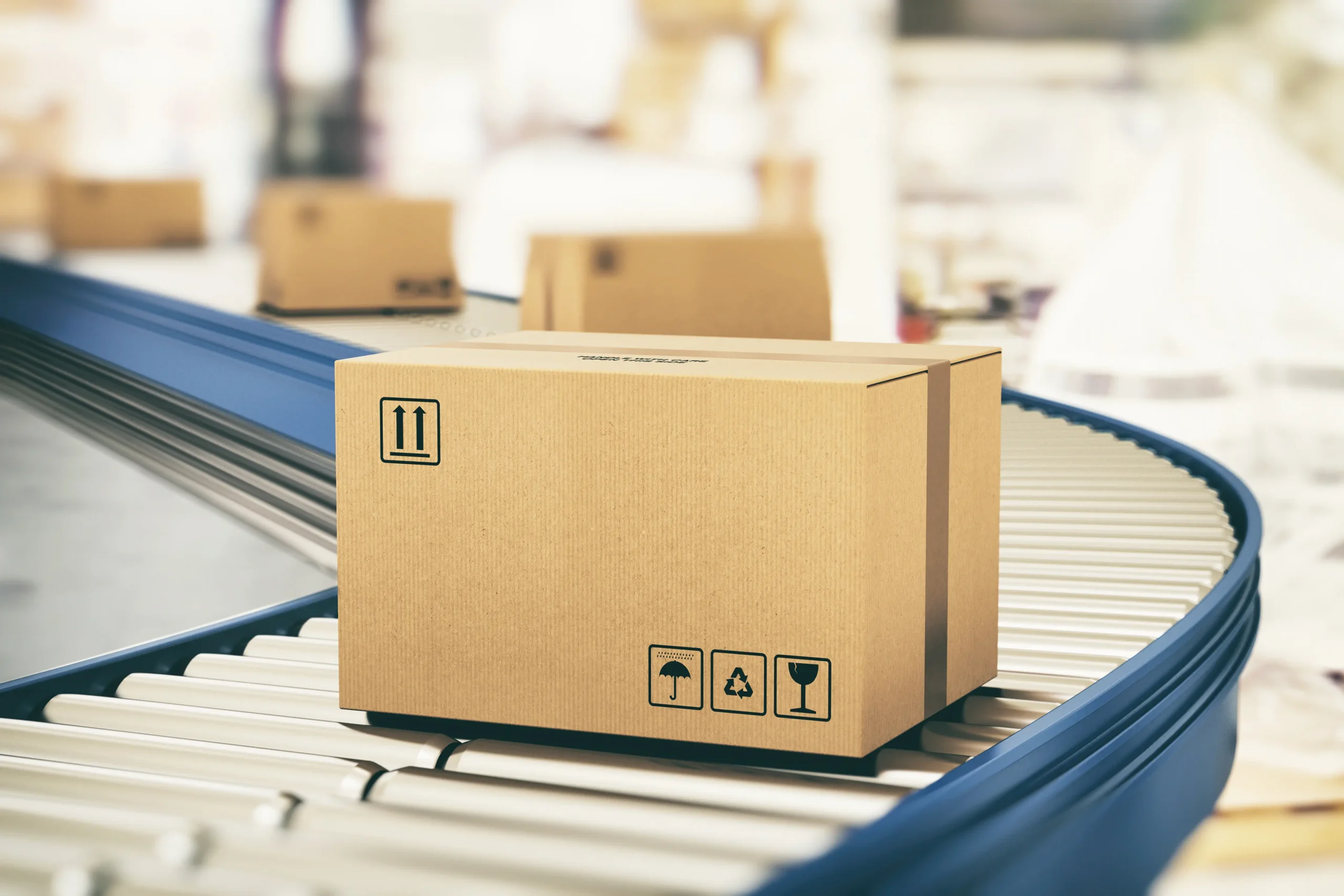 Cardboard box with shipping symbols placed on a conveyor belt in a warehouse setting.