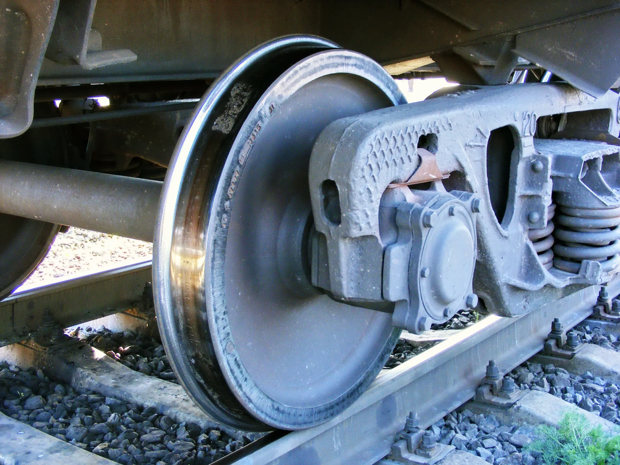 Close-up view of a train wheel on the track, showing detailed components and rail.